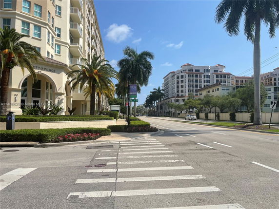 Front view of a multi-story residential building with balconies and palm trees.