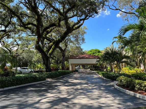 Pathway leading to a building entrance surrounded by trees and landscaped greenery.