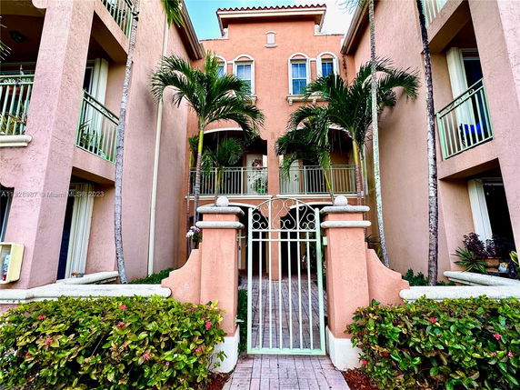 Front view of a multi-story building with balconies and an ornate gate.