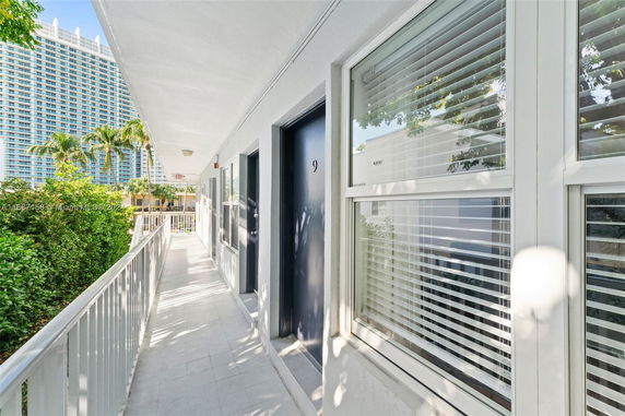 Corridor view with apartment doors and a tall building in the background.