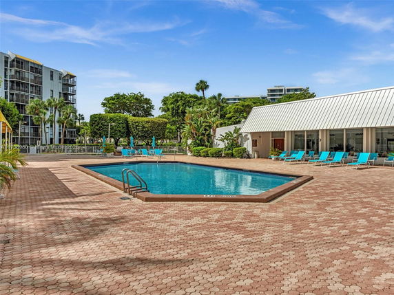 Outdoor swimming pool area with lounge chairs and surrounding greenery.