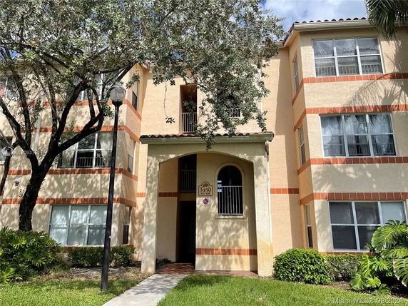 Front view of a multi-story apartment building with cream and red brick accents.