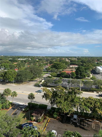 View from a higher vantage point showing roads, parking areas, and a landscape with trees and residential buildings.