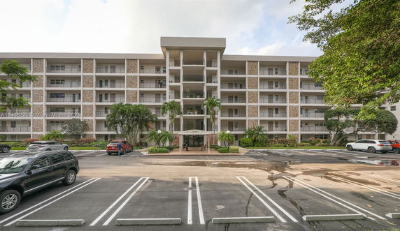 Front view of a multi-story apartment building with balconies and a central entrance.