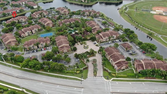 Aerial view of a residential complex with multiple buildings and a surrounding water feature.