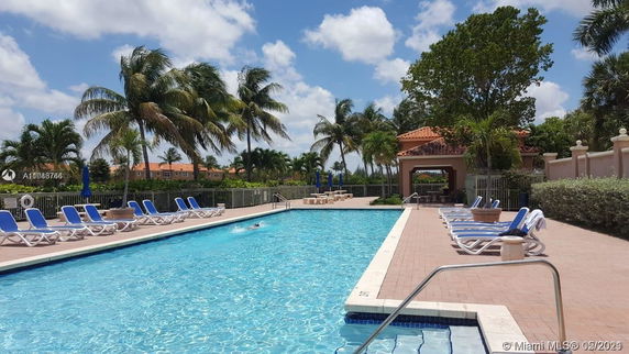 Outdoor swimming pool area with lounge chairs and a small pavilion.