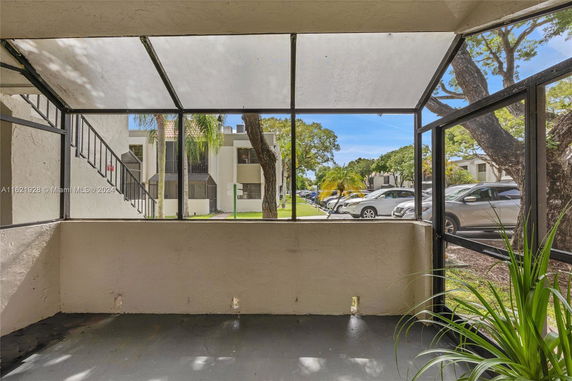 View from a covered area looking towards an outdoor parking lot and adjacent buildings.