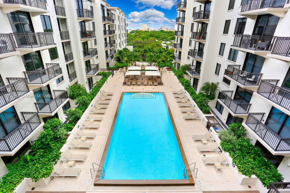 Outdoor swimming pool area surrounded by multi-story buildings with balconies.
