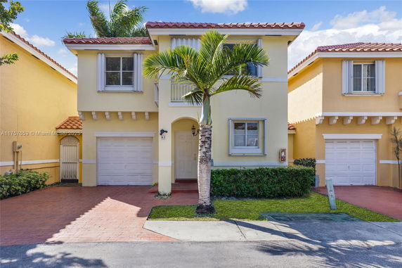 Front view of a two-story house with a single garage and palm tree.