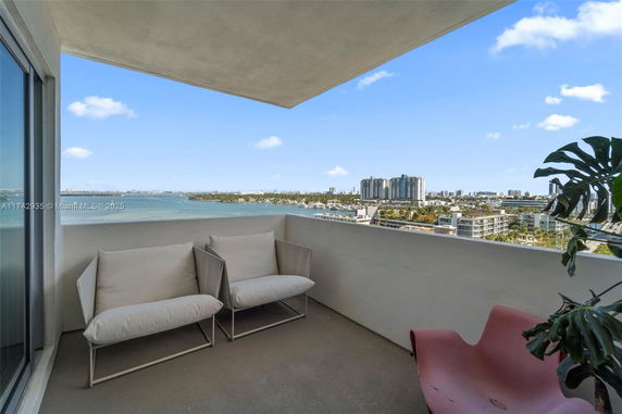 Outdoor balcony with seating overlooking a cityscape and waterfront.
