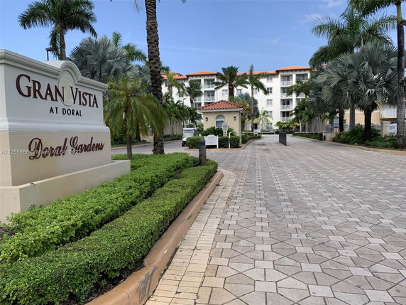 Front view of a multi-story residential building with tiled roofs and palm trees.