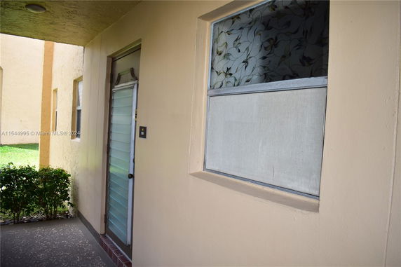 Exterior view of an entrance with a door and a decorative window.