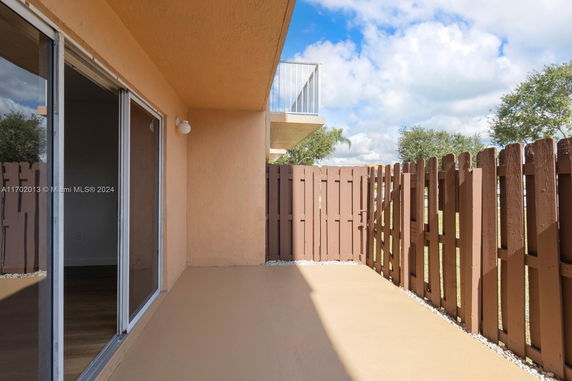 Outdoor patio area with wooden fence and sliding glass doors.