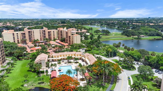 Aerial view of a residential complex with multiple buildings and a central swimming pool, surrounded by greenery and a golf course.