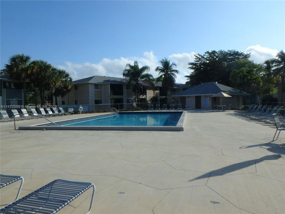 Outdoor swimming pool area with lounge chairs and surrounding buildings.