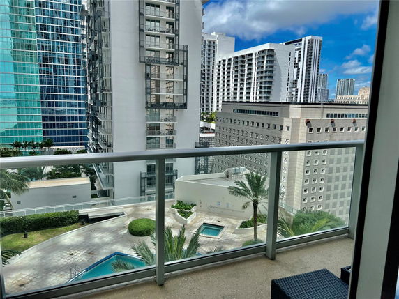 Panoramic view from a balcony overlooking modern high-rise buildings with a swimming pool below.