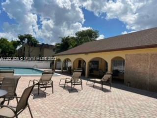 Outdoor swimming pool area with loungers and a poolside building.
