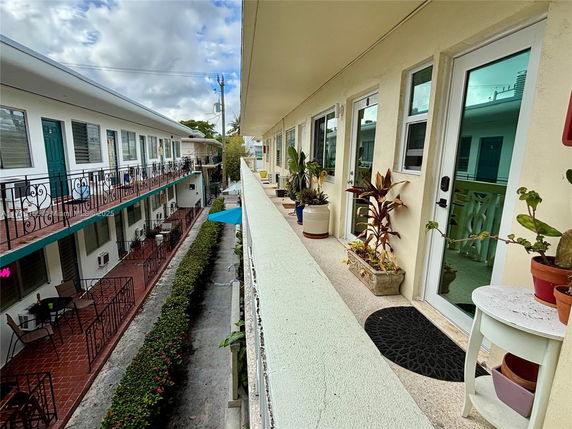 View of a multi-story residential building with balconies and potted plants.