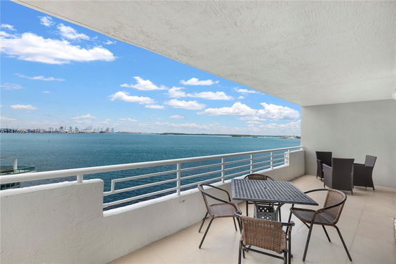 Rooftop balcony with outdoor furniture, overlooking a large body of water.