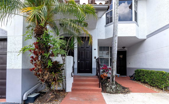 Front view of a house entrance with plants and shrubs.