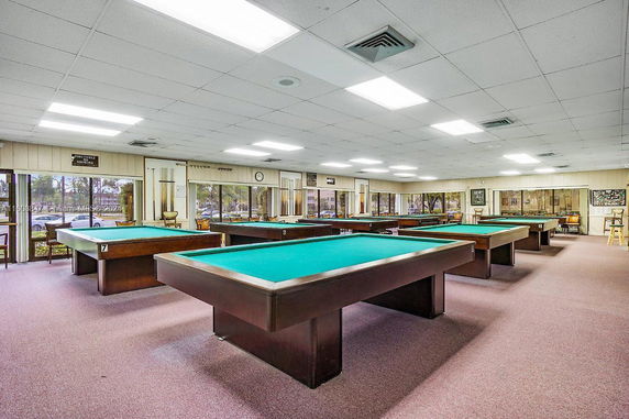 Billiards room with multiple pool tables and large windows.