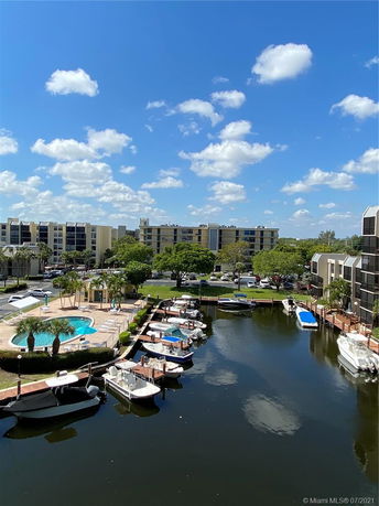 Panoramic view of residential buildings with a canal, boats, and a swimming pool area.