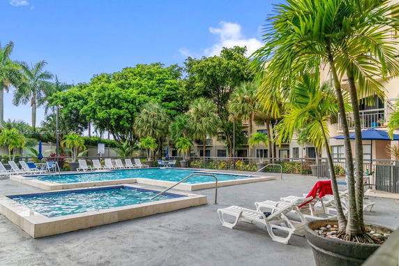 Outdoor swimming pool area with deck chairs and surrounding palm trees.