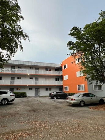 Front view of a multi-story apartment building with an orange and white facade.