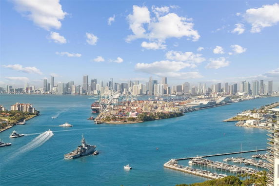 Panoramic view of a waterfront cityscape with buildings and boats.