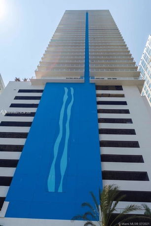Front view of a tall modern building with blue and white facade.