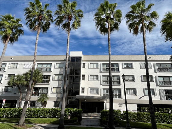 Front view of a multi-story residential building with palm trees.