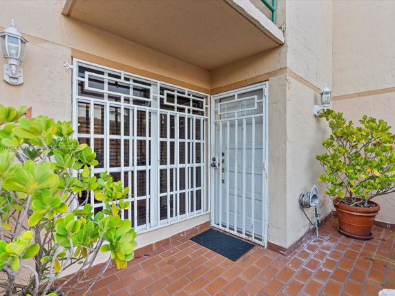 Front view of a building entrance with metal security bars and outdoor plants.