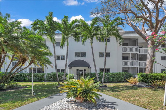 Front view of a multi-story residential building with balconies and a central entrance.