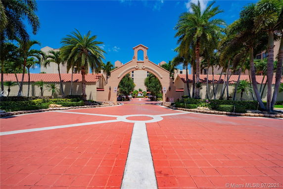 Front view of a building with an arched entrance surrounded by palm trees.