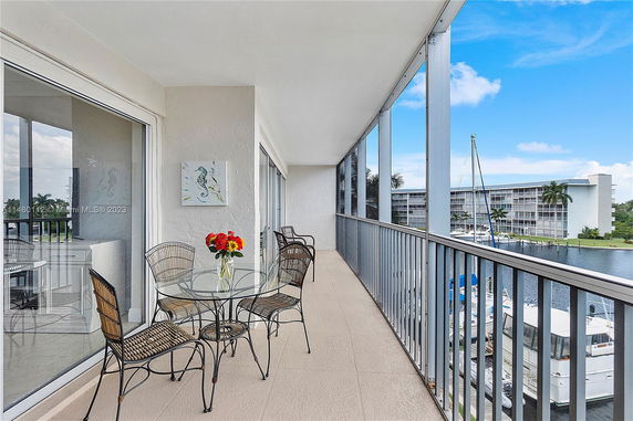 Balcony view with outdoor chairs and table overlooking water and buildings.