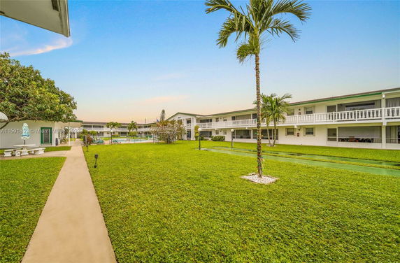 View of a residential complex with grass lawn and palm trees.