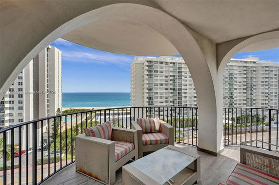 Balcony with arch view overlooking ocean and buildings.