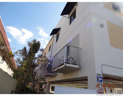 Side view of a multi-story building with balconies and awnings.