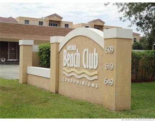 Front view of a condominium building with a prominent entrance sign reading 'Beach Club Condominiums.'