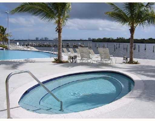 Outdoor pool area with a view of palm trees and a body of water in the background.