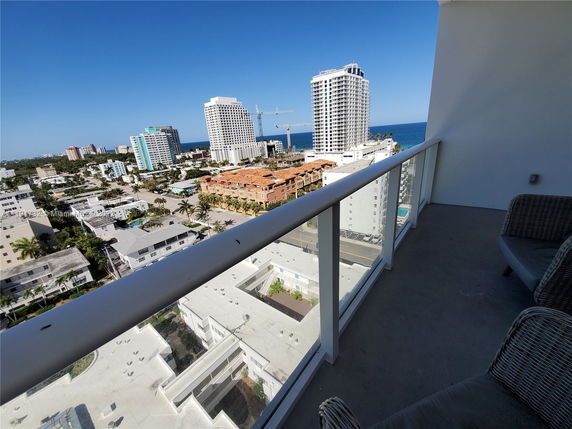 View from a high-rise building balcony overlooking surrounding buildings and the ocean.