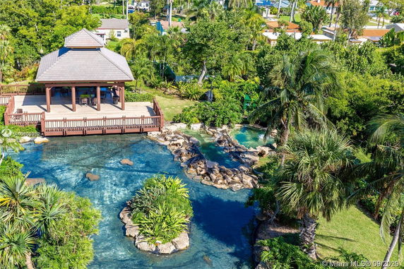 Aerial view of a gazebo by a pond with lush greenery.
