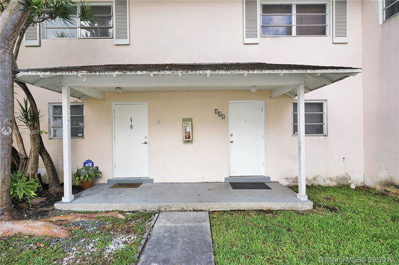 Front view of a two-story building with two entrance doors under a small porch.