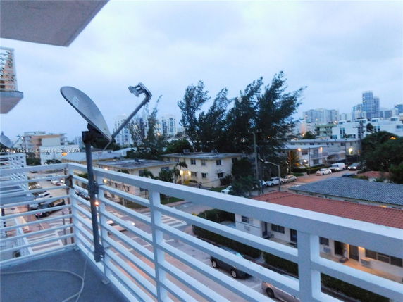 View from a balcony overlooking residential buildings and trees in an urban area.