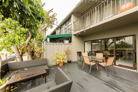 Outdoor patio area of a residential house with seating and dining table, adjacent to sliding glass doors.