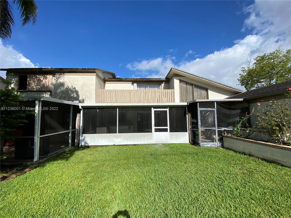 Back view of a two-story house with screened patio and large windows.