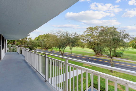 Balcony view overlooking a green landscape with trees and a road.