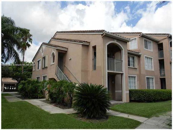 Front view of a multi-story residential building with balconies and a landscaped entrance.