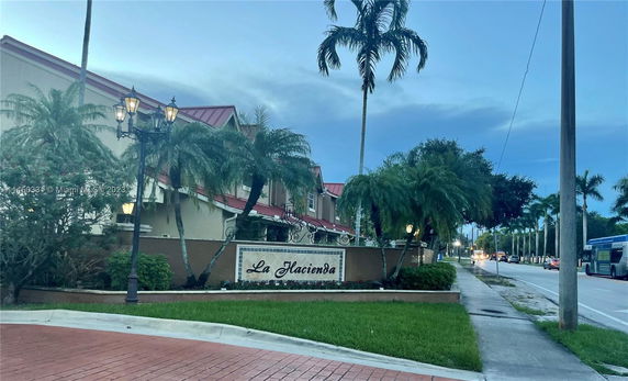 Front view of a building with a sign reading 'La Hacienda' and surrounded by palm trees.