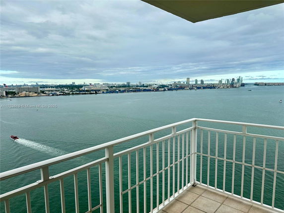 Panoramic view from a high-rise balcony overlooking a body of water and city skyline.